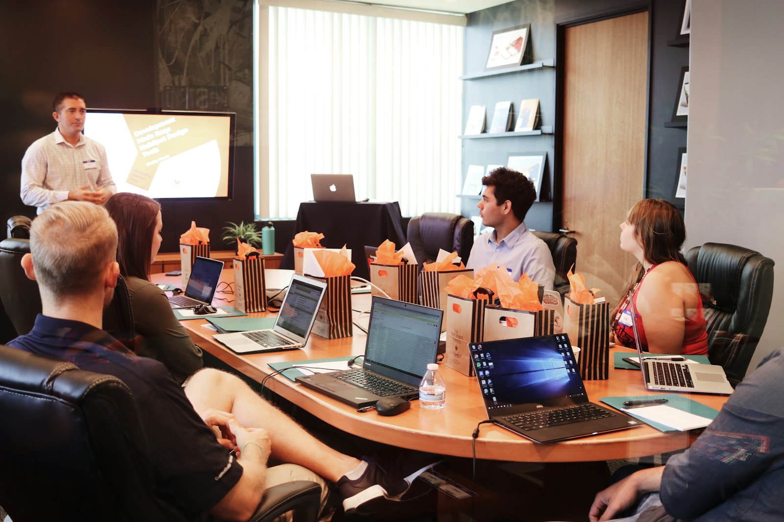 A team meeting around a long table with a presenter at the screen